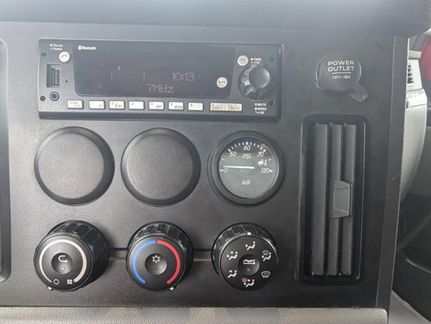 Dashboard controls of a 2022 Freightliner Cascadia 126 showing radio head unit, multiple circular gauges, climate control knobs, and a vertical vent.