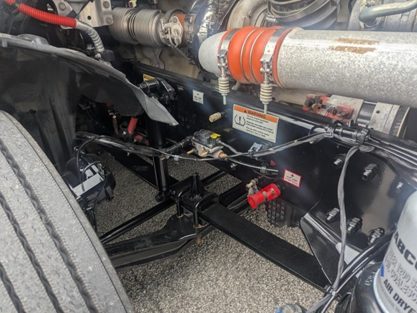Freightliner Cascadia 126 engine bay showing hydraulic hoses, coolant lines, and chassis components under the cab.