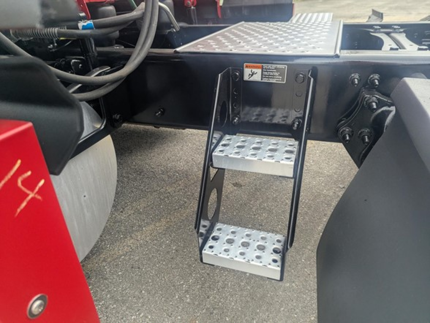 Freightliner Cascadia truck undercarriage showing aluminum foldable step/ladder with perforated treads attached to frame.