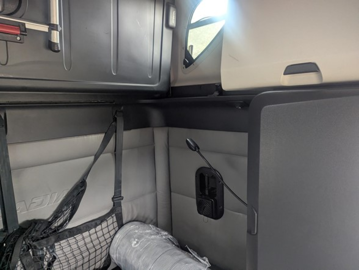 Freightliner Cascadia 126 sleeper cab interior showing upper bunk area and side panel with a small storage pocket and wiring harness.