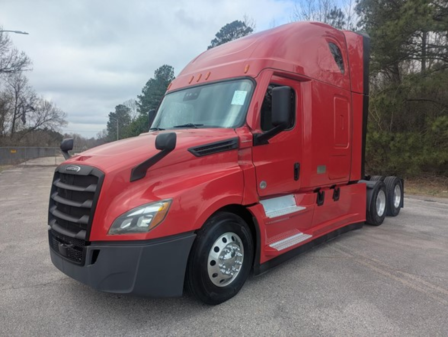Freightliner Cascadia 126 sleeper cab tractor in red, side view, shows front grille, hood, windshield, mirrors, and dual rear axles.