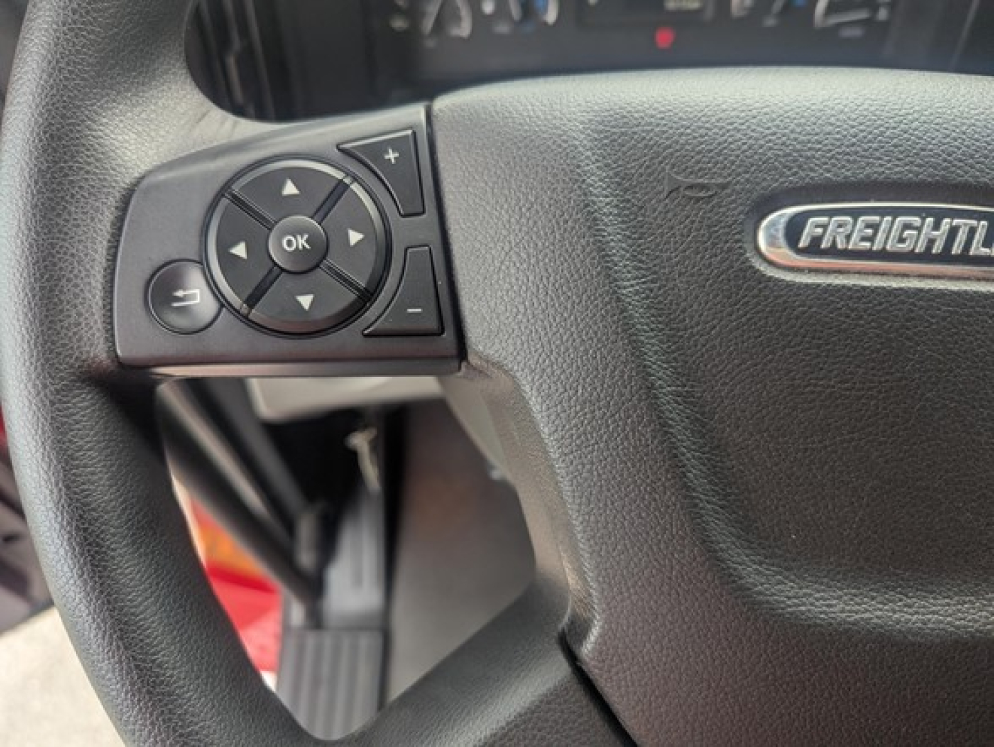 Steering wheel of a 2022 Freightliner Cascadia 126 showing control pad with OK button and navigation arrows
