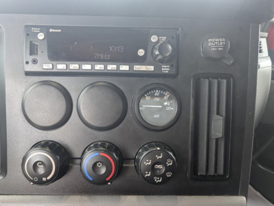 Dashboard controls of a 2022 Freightliner Cascadia 126 showing radio head unit, multiple circular gauges, climate control knobs, and a vertical vent.
