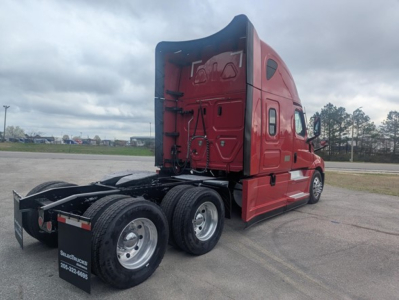 Truck cab and chassis of a red 2022 Freightliner Cascadia 126 with sleeper cab rear view showing dual rear axles