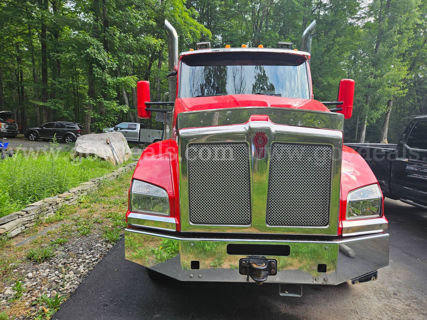 Kenworth T880 front view showing chrome grille, large bumper, and red cab with high exhaust stacks.