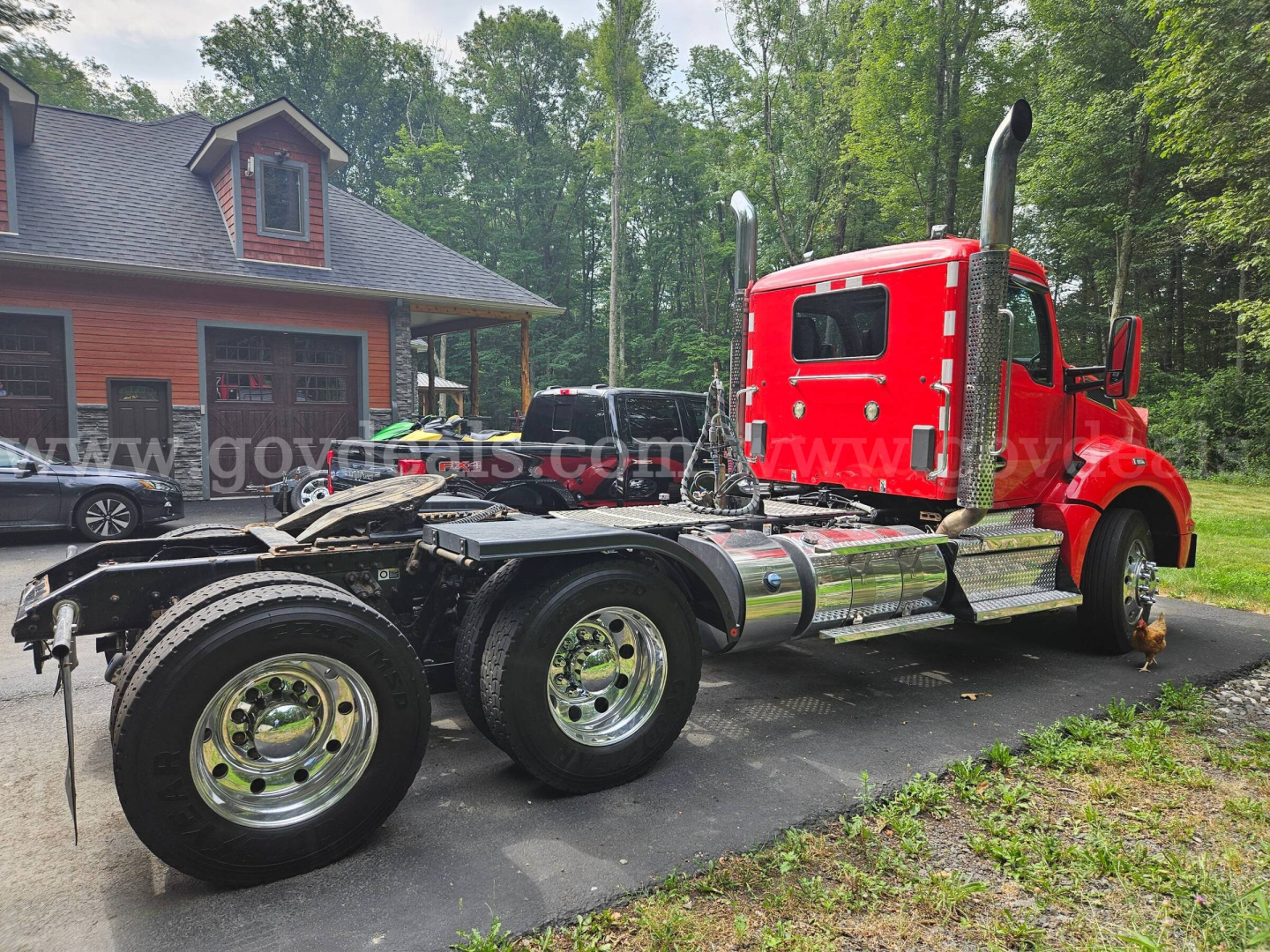 Kenworth T880 tractor truck (red) in a used condition, side view showing chassis, dual rear axles, chrome fuel tanks, and exhaust stacks.