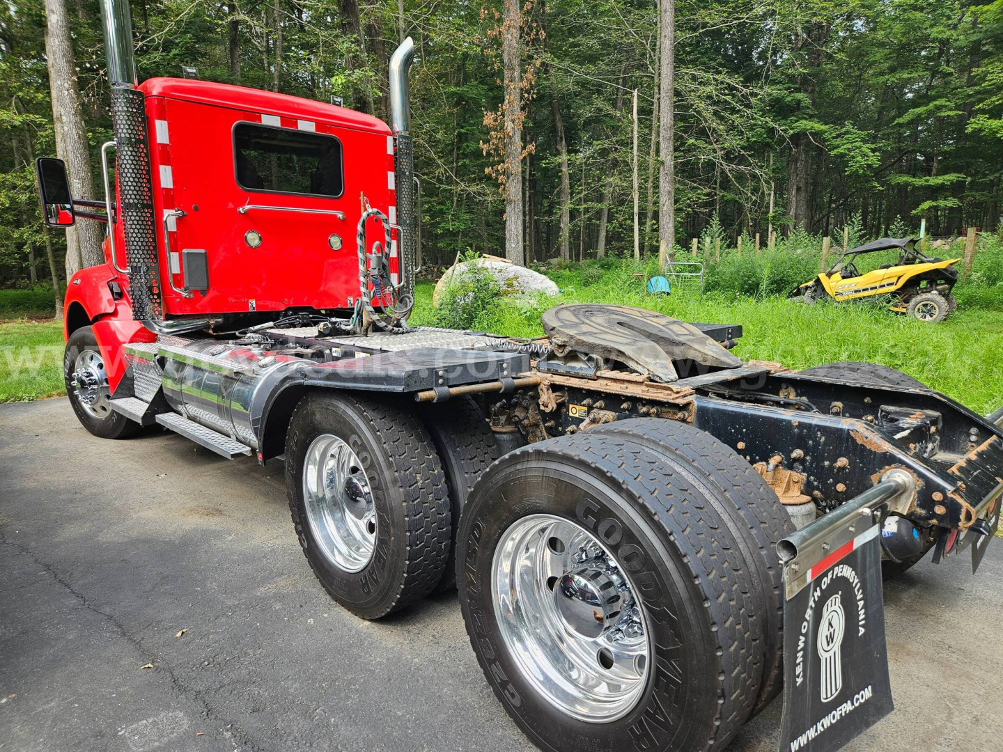Kenworth T880 truck chassis with red cab and exposed rear frame showing dual rear axles and wheels.