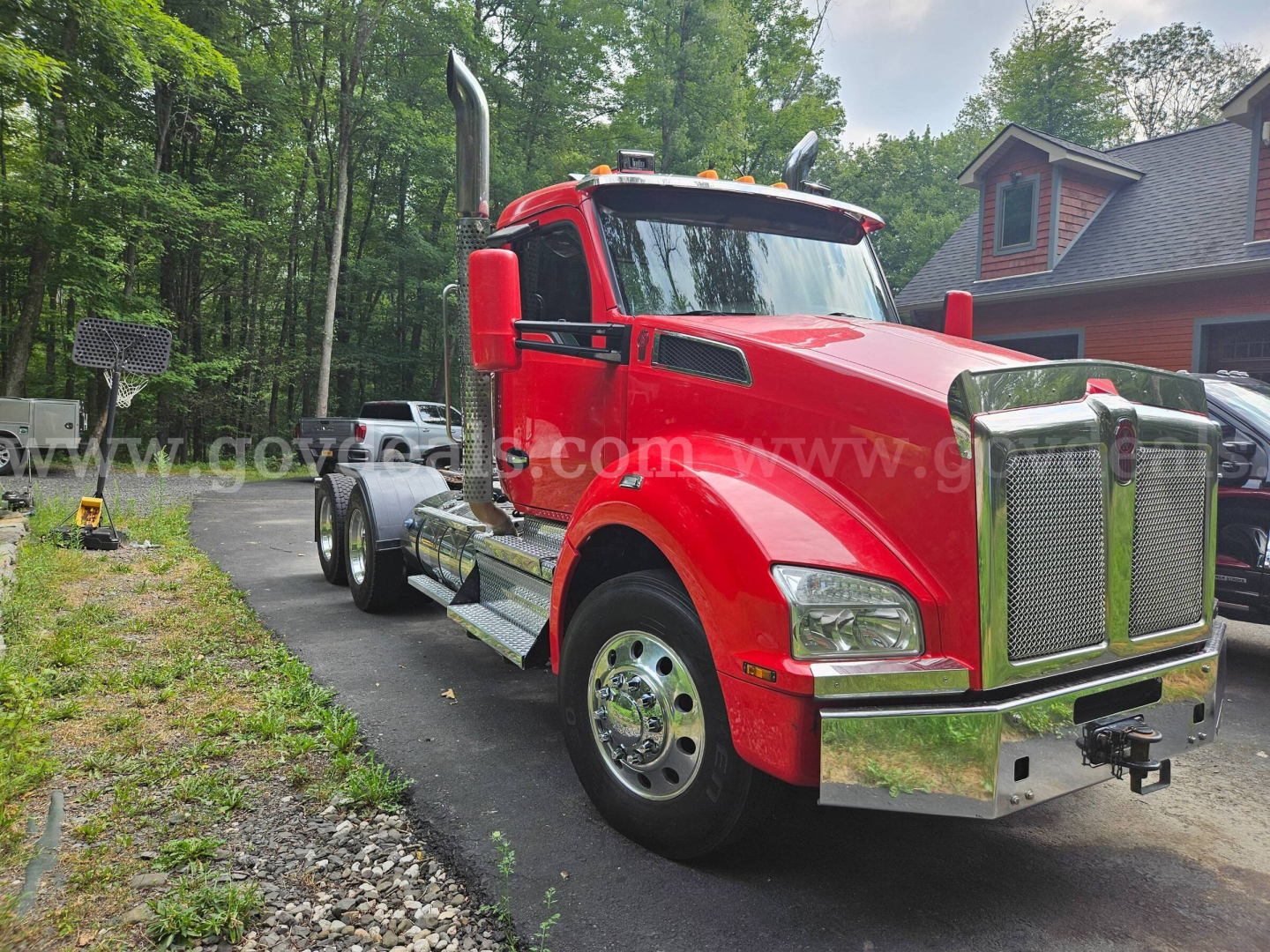 Kenworth T880 truck front-left view showing red cab and chrome grille and bumper with dual exhaust stacks.