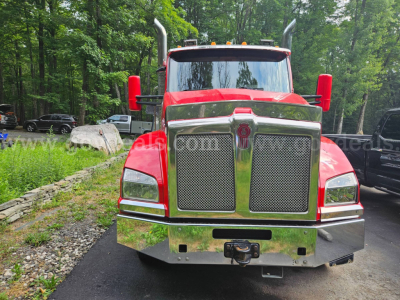 Kenworth T880 front view showing chrome grille, large bumper, and red cab with high exhaust stacks.