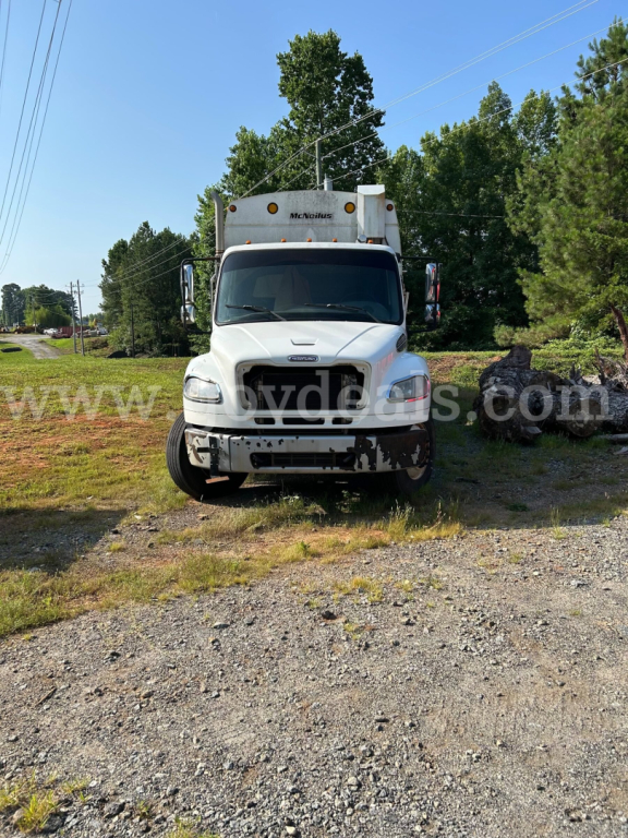 Front view of a white Freightliner M2 106 dump truck with McNeilus box, used condition, VIN 1FVHCYBS7DHFB9919, stock 790-335, on gravel lot.