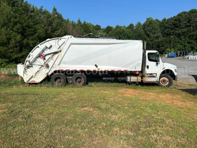Freightliner M2 106 dump truck side view showing large white dump body with rear discharge mechanism and cab with two-tone bumper.