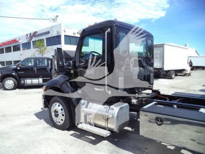Kenworth T280 truck side view showing fuel tanks and cab, rollback in background.