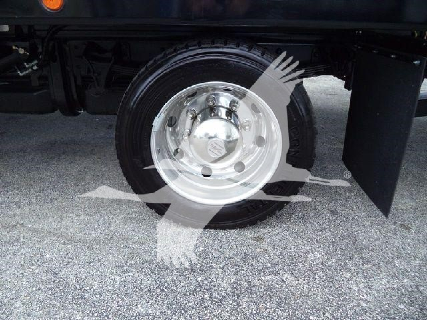 Truck wheel and chrome hubcap under rear of 2023 Chevrolet Silverado 6500HD rollback truck.
