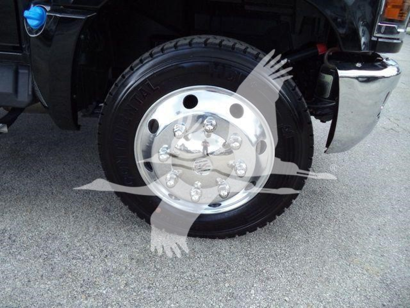 Front wheel showing chrome hubcap and black tire on Silverado 6500HD rollback truck with partial fender and chrome bumper.