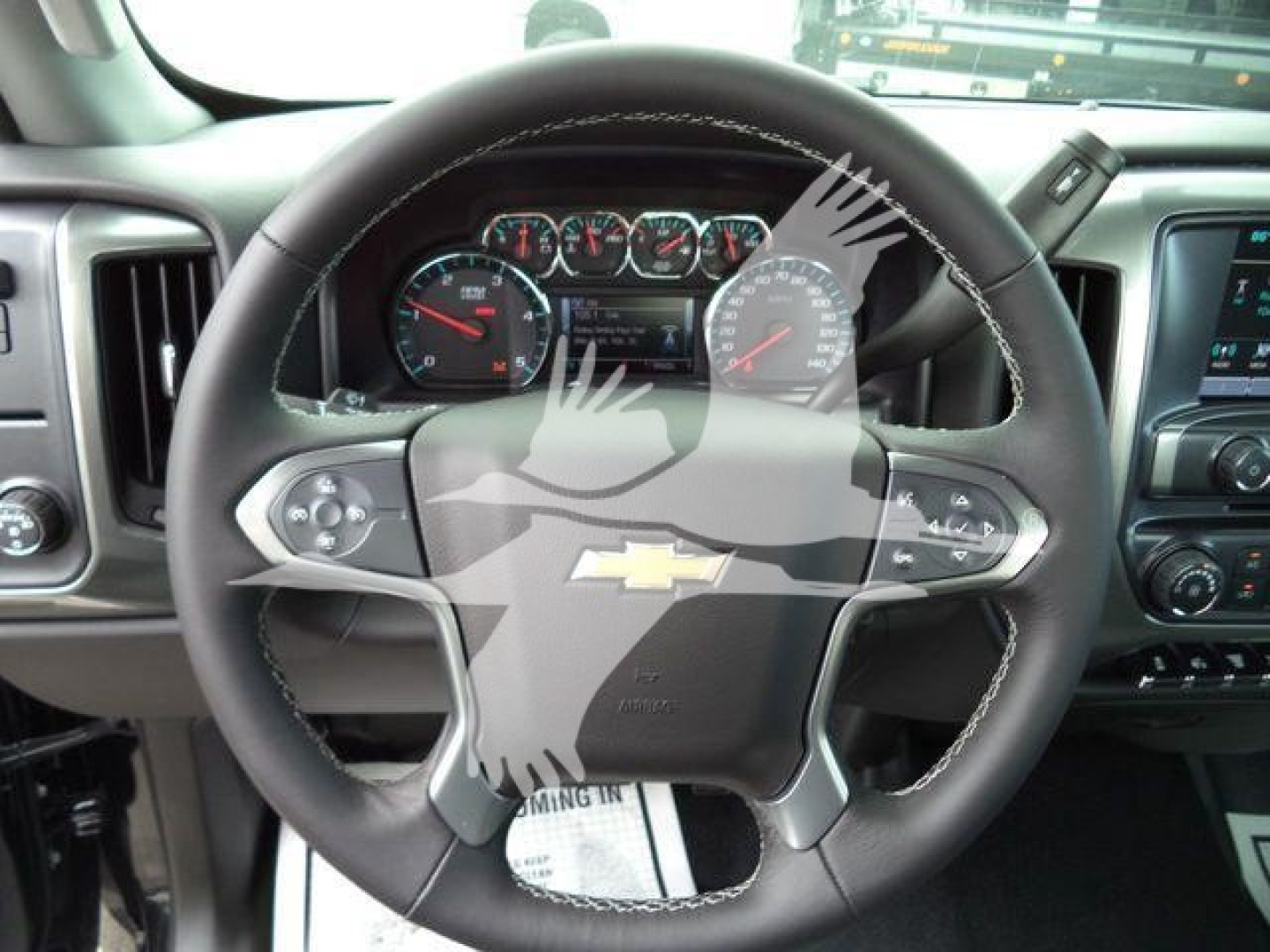 Chevrolet Silverado 6500HD dash and steering wheel interior view with Chevrolet logo center. Dashboard gauges visible through steering wheel.