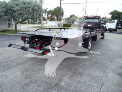 Flatbed tow truck with Silverado 6500HD badge and loading ramp extended.