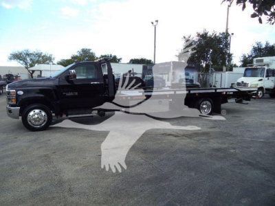 Truck bed with rollback equipment on a black Chevrolet Silverado 6500HD in a dealership lot.