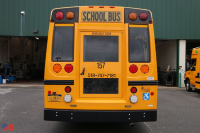 Ford E450 school bus rear view with wheelchair lift, yellow body, school bus signage, emergency door, and contact numbers visible.
