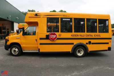 Ford E450 school bus with wheelchair lift, side view showing Hudson Falls Central School lettering and stop sign emblem.