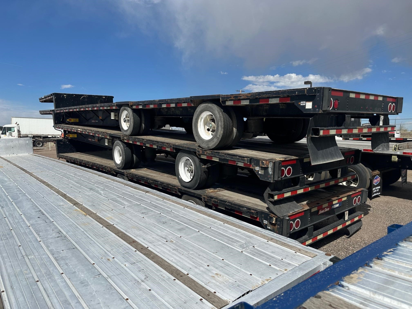 Great Dane spread air drop deck trailer stacked on top of other trailers showing multiple axles and metal decking.