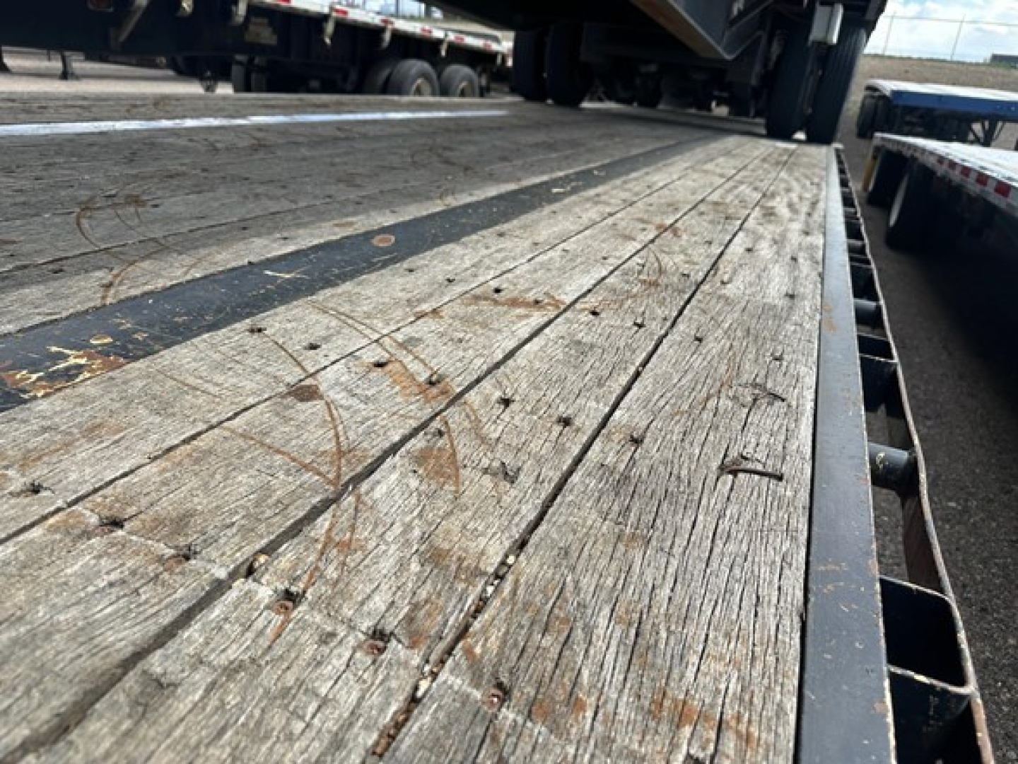 Great Dane steel spread air drop deck trailer bed showing wooden planks with weathered surface and metal edgeWear.
