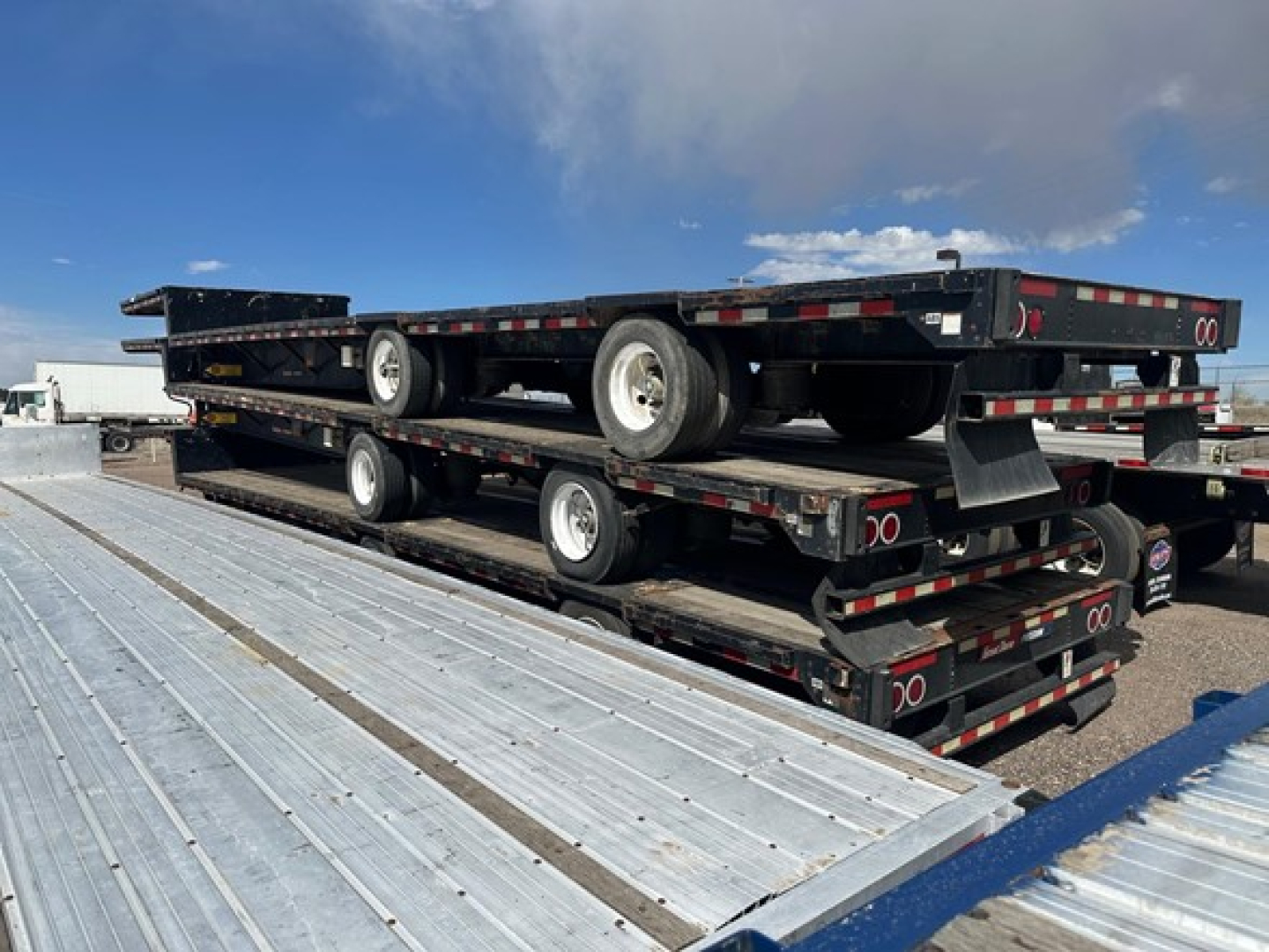 Great Dane steel spread air drop deck trailer stacked on another with multiple axles and wheels visible.