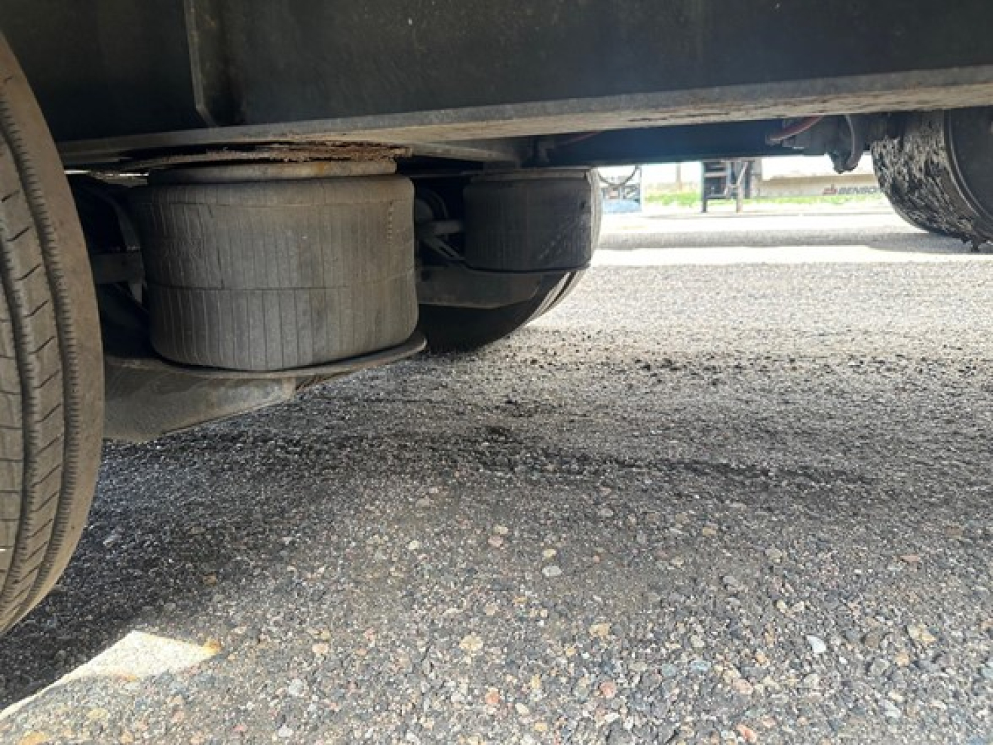 Underneath view of a Great Dane drop deck trailer showing the air ride suspension with large cylindrical airbags and metal framework.