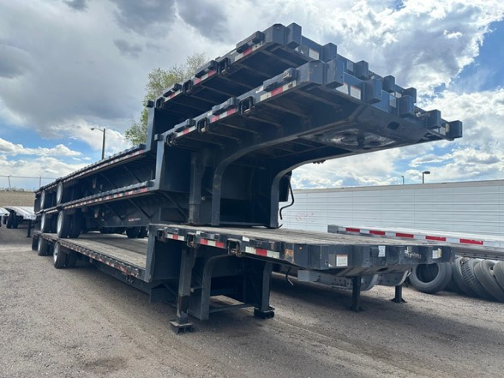 Great Dane steel spread air drop deck trailer shown from side and front angle with stacked components and support beams.