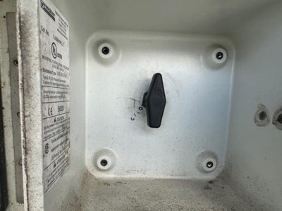 Drop deck trailer interior with a black toggle lever in a white recessed panel and warning label on the left side.