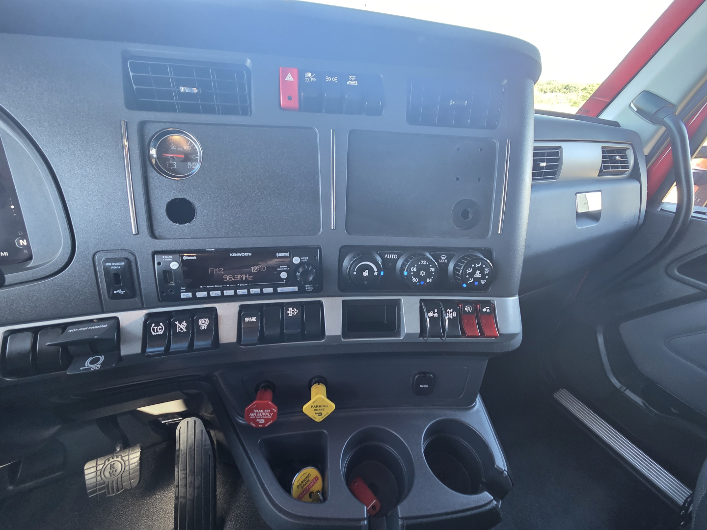 Cab interior of a 2023 Kenworth T680 showing instrument cluster area, dash switches, and ignition area with KC controls.