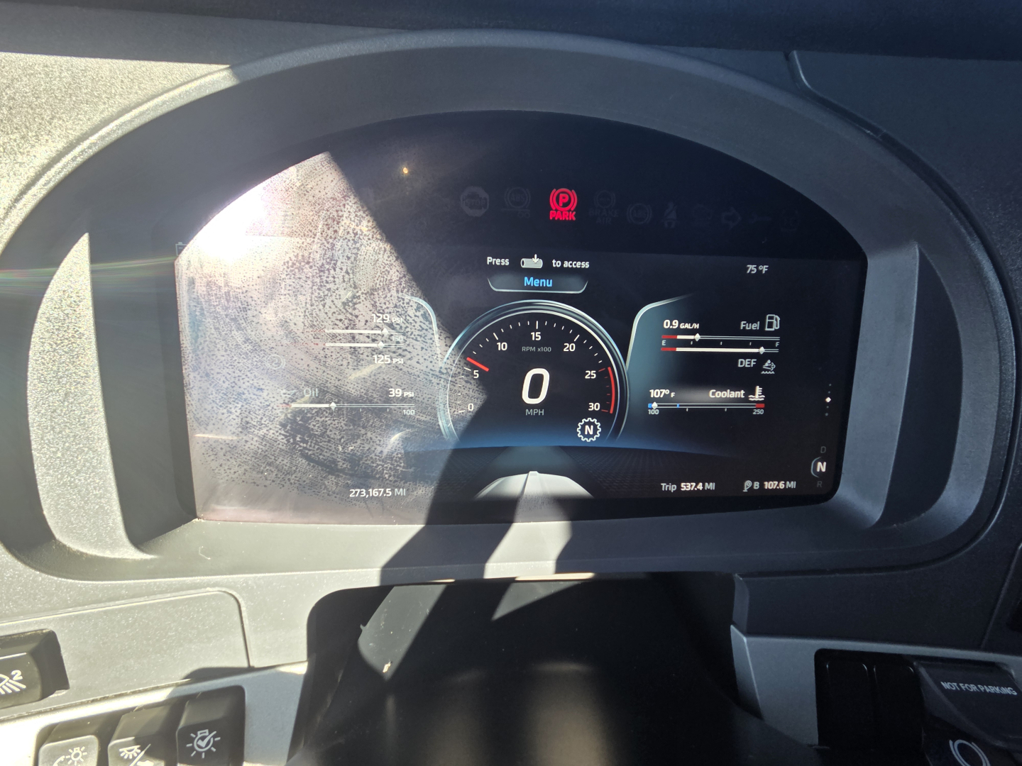 Kenworth T680 dashboard cluster showing digital gauges in a truck cockpit with 0 MPH, fuel, DEF, coolant indicators visible.
