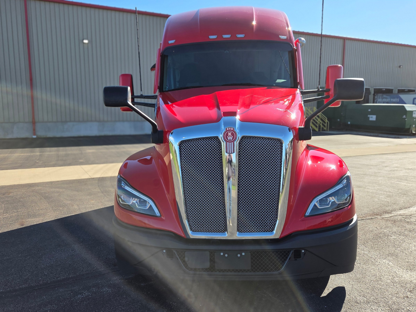 Kenworth T680 truck front view showing chrome grille and headlights with red cab.