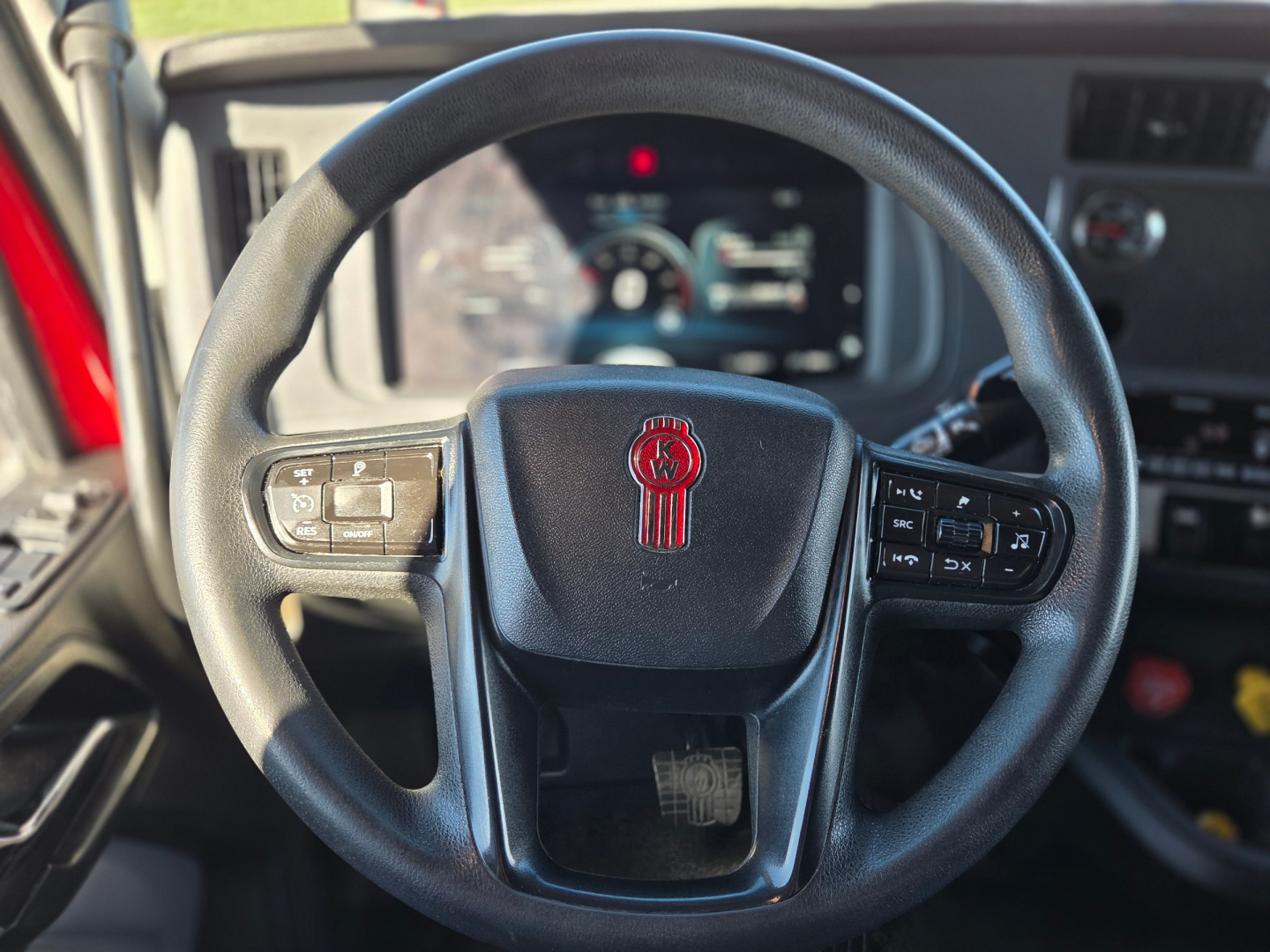 Kenworth T680 steering wheel and dashboard interior with digital gauges visible through the steering wheel.