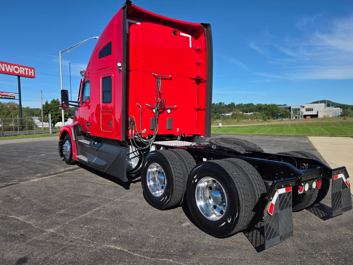 Kenworth T680 tractor with bright red cab, rear view showing dual rear axles and chassis fittings, no visible text on component labels.