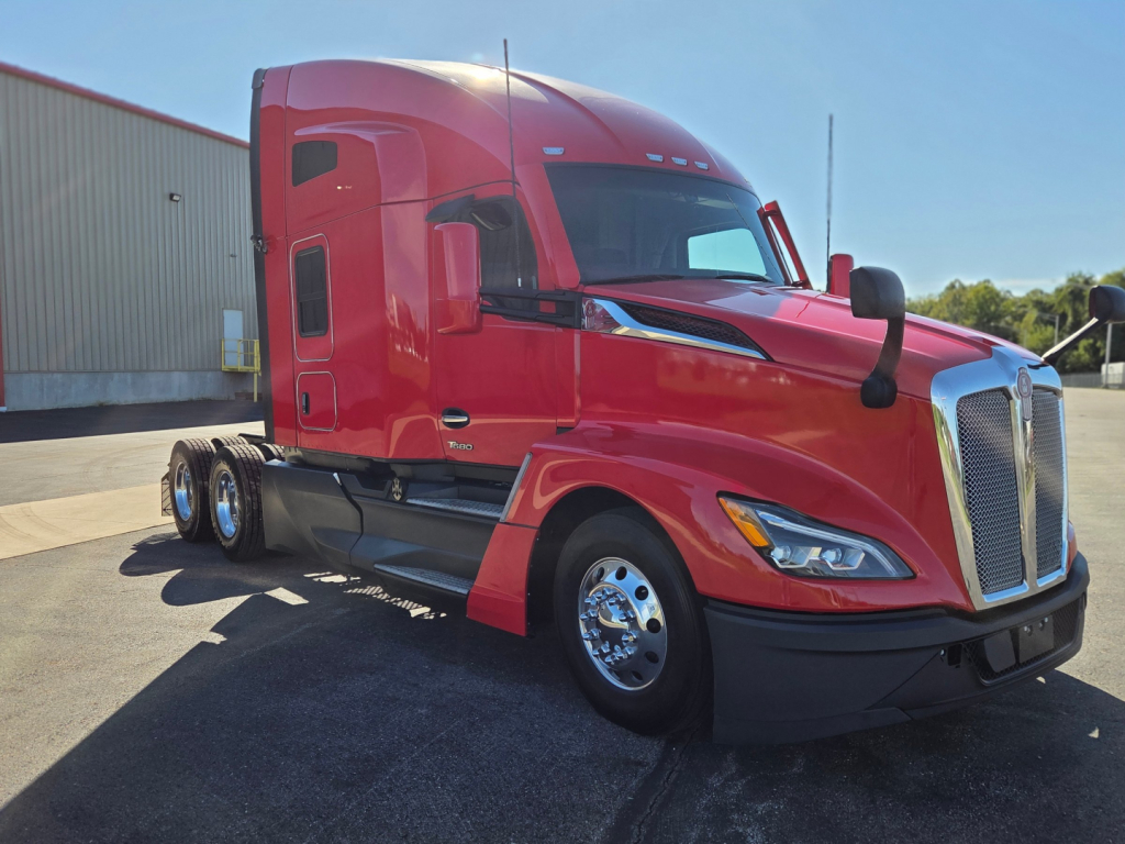 Kenworth T680 semi-truck in red, side view showing cab and front grille, chrome wheels, dual rear axles, daytime exterior.