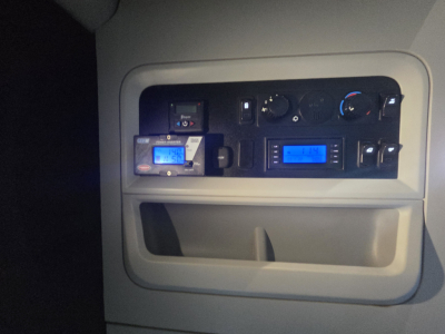 Dashboard controls panel of a Kenworth truck showing gauges and switches. Visible text includes various small labels and digital displays