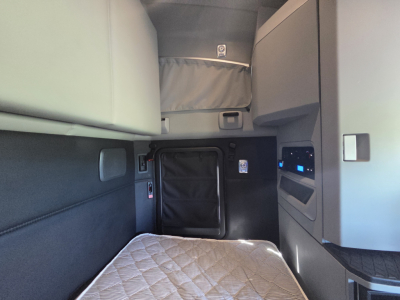 Kenworth T680 sleeper cab interior showing overhead storage, side panel, and quilted mattress in the bunk area.