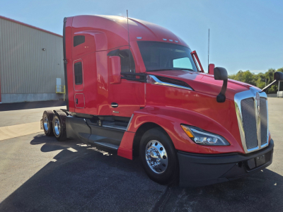 Kenworth T680 semi-truck in red, side view showing cab and front grille, chrome wheels, dual rear axles, daytime exterior.