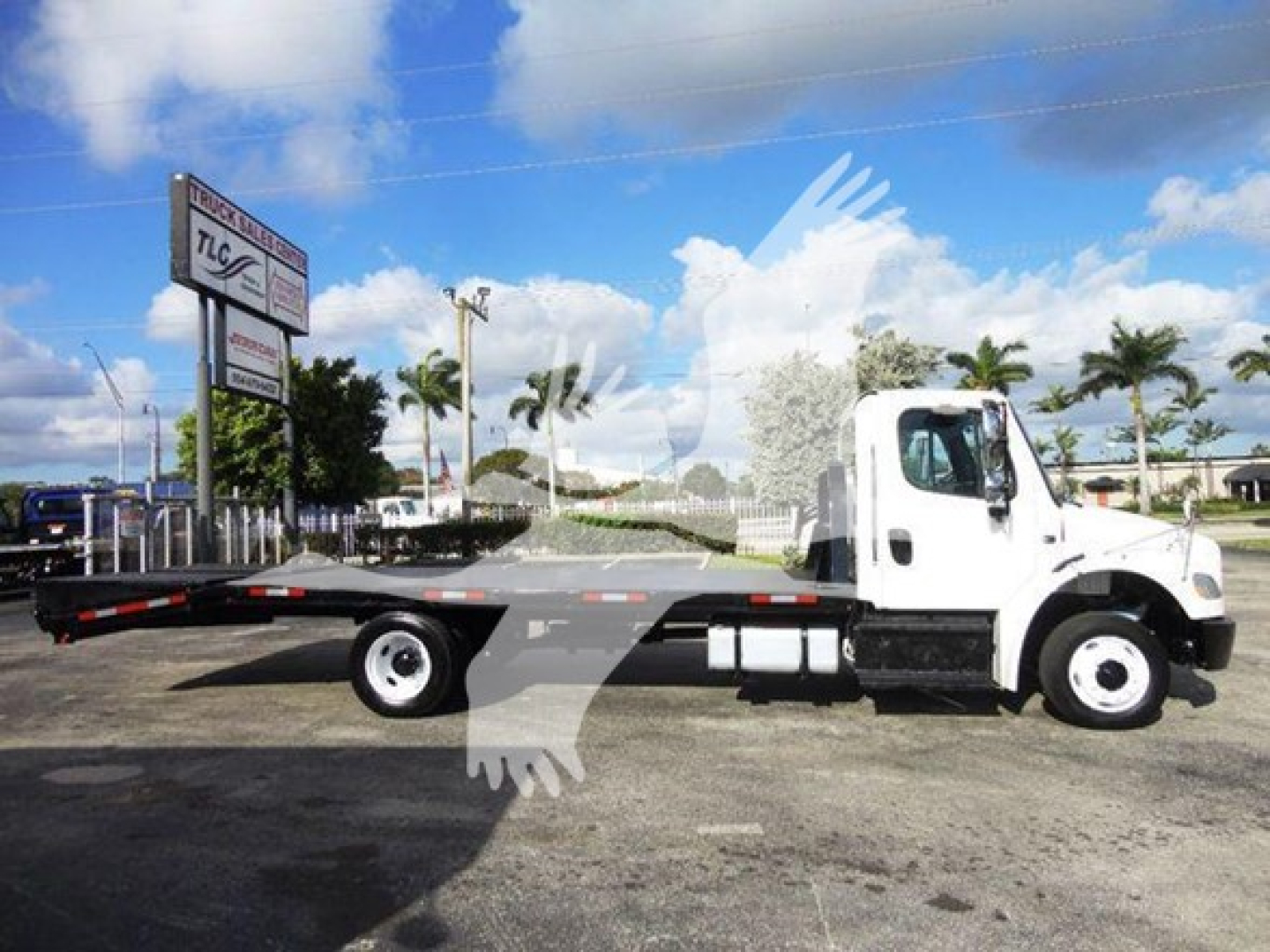 Flatbed tow truck side view showing 2015 Freightliner M2 106 with long flatbed and white cab.