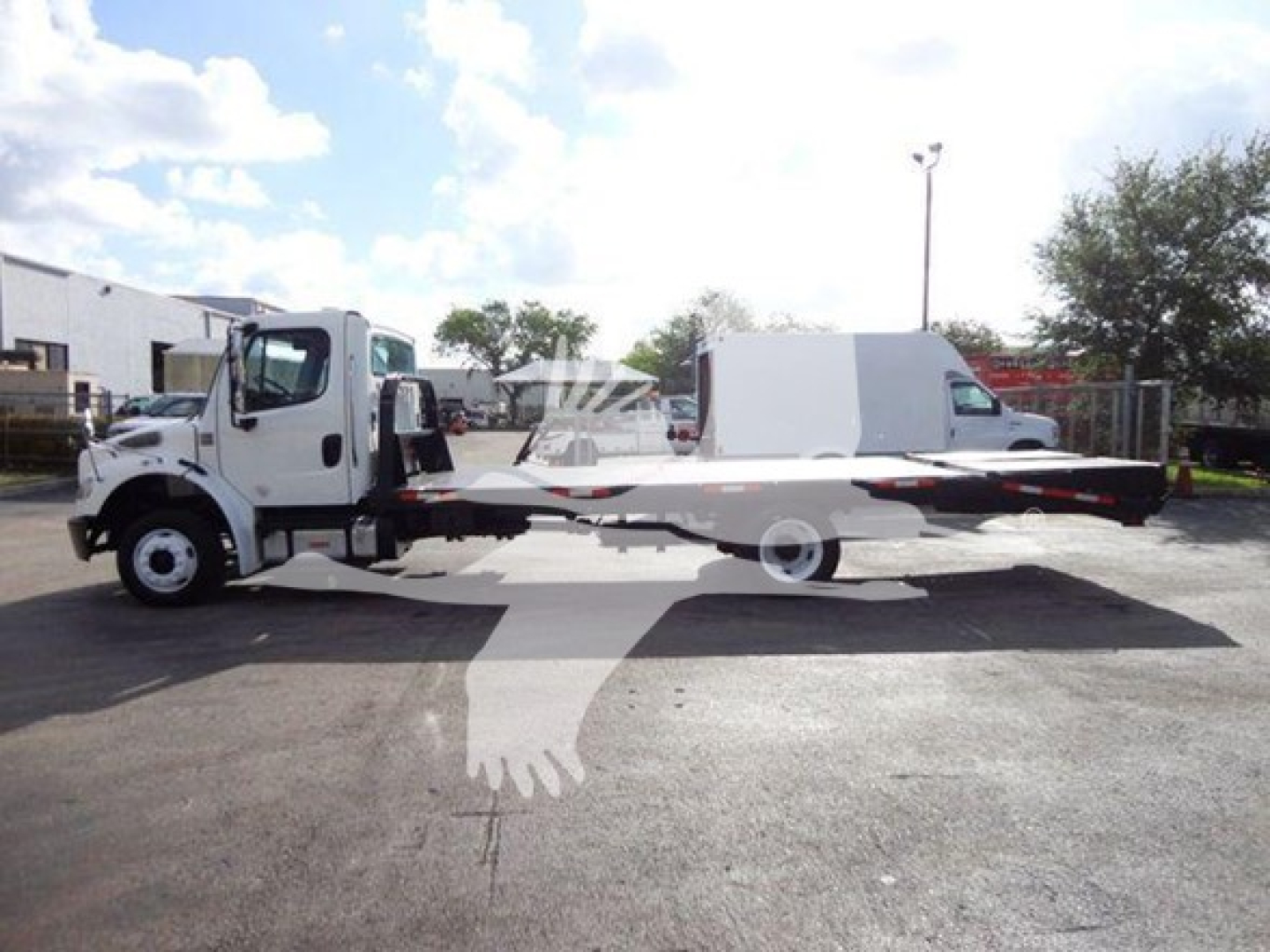Flatbed tow truck side view showing Freightliner M2 106 with cab, wheelbase, and long flatbed bed.