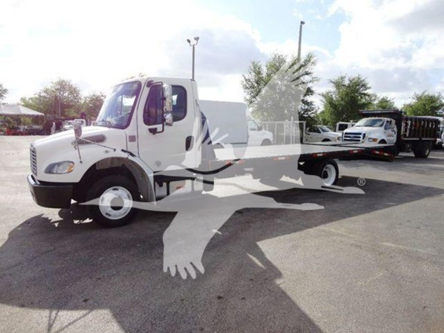 Truck: Freightliner M2 106 flatbed with cab and long flatbed, front view left side showing white body.
