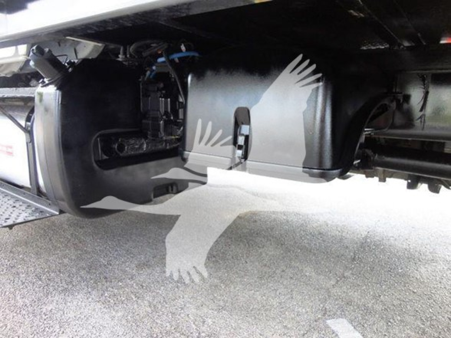 Underneath Freightliner M2 106 showing fuel/oil lines and undercarriage components near cab area.