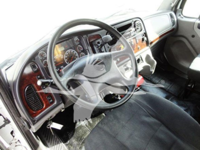 Truck cabin interior with steering wheel and dashboard of a Freightliner M2 106 showing instrument cluster and woodgrain trim