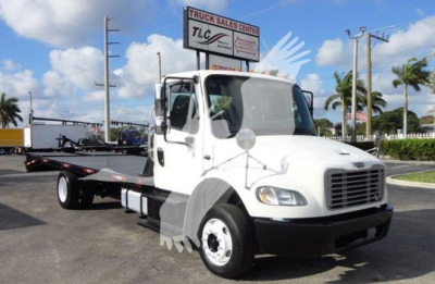 Flatbed tow truck in white cab with long wheelbase, front grille, dual side mirrors, and flatbed bed visible, Freightliner M2 106 style.