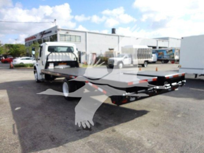 Flatbed tow truck with lowbed trailer attached to Freightliner M2 106, white cab, black flatbed, outdoor lot