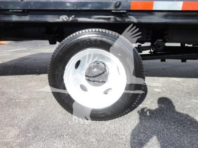 Flatbed truck wheel and partial undercarriage of a 2015 Freightliner M2 106 showing a single steel wheel with tire mounted on truck chassis.