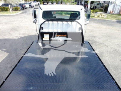 Flatbed truck bed with Freightliner emblem on cab-back area, metal diamond-plate surface visible.