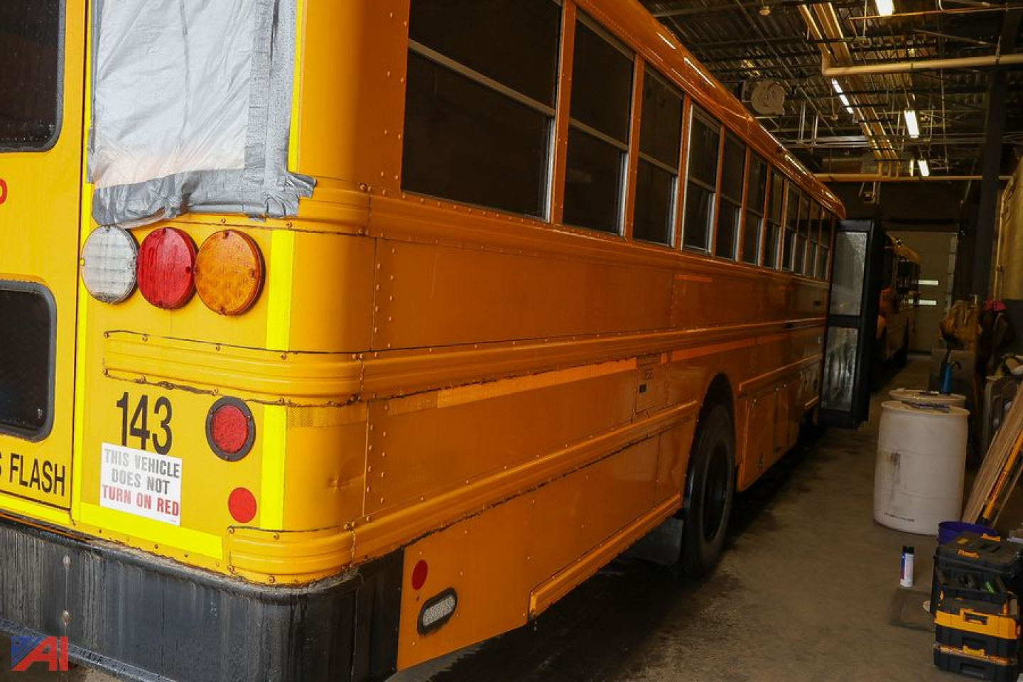 School bus tail showing 143 and rear lights in a workshop.