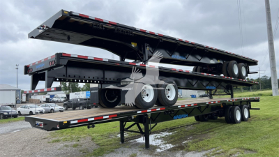 Flatbed trailer with steel air slider in raised position, dual tandem axles, black frame, red/white reflective tape along edges, Wabash branding on side.