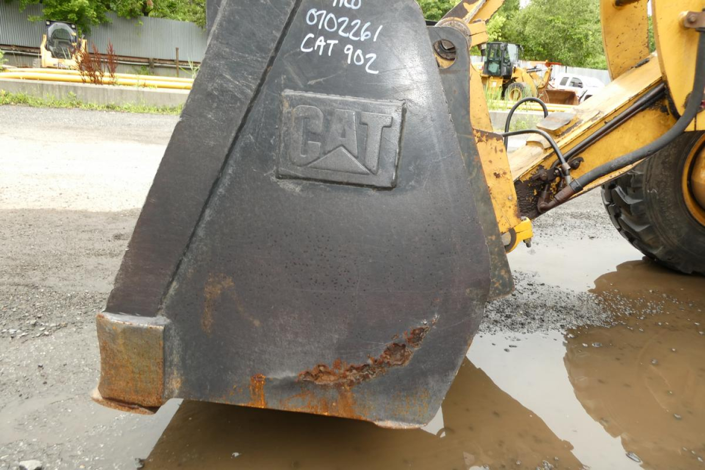 Caterpillar 902 bucket of wheel loader showing CAT embossed bucket with rust and dirt near ground